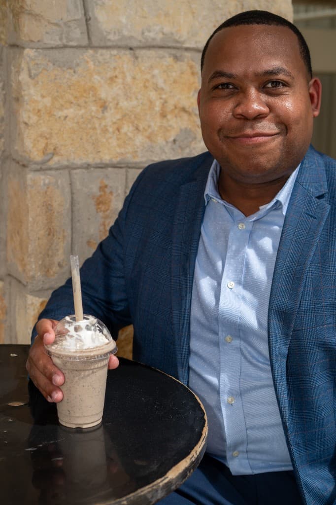 Joshua Edmond at a local Buda cafe, smiling with a drink
