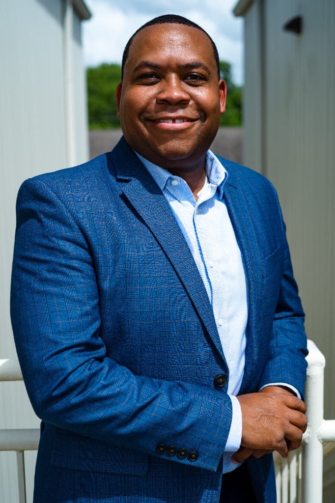 Professional portrait of Joshua Edmond in a blue plaid blazer